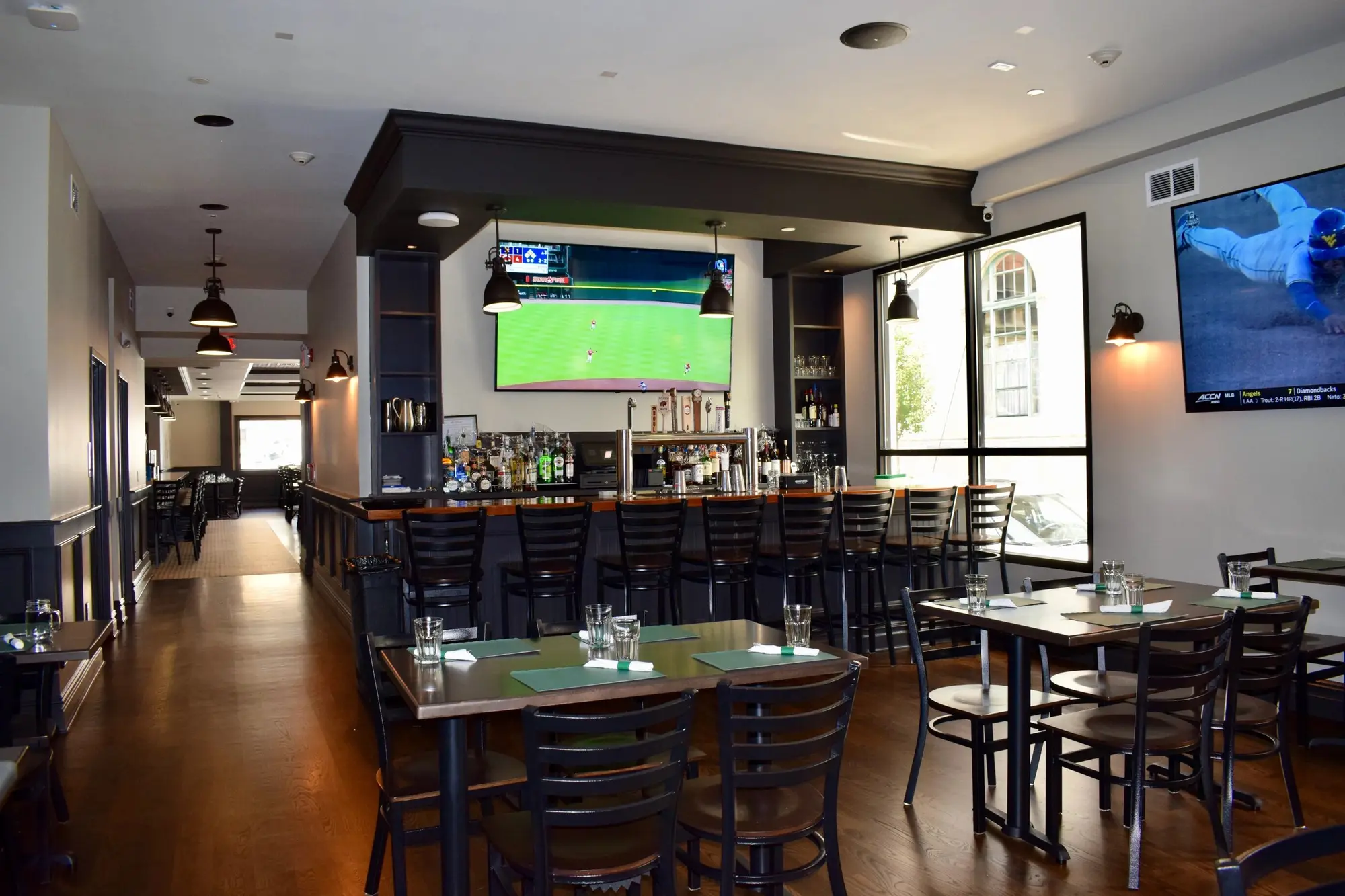 The long bar and dining tables, with a game on the TV at the far end.